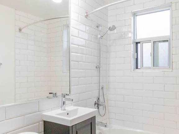 A white bathroom with a sink, mirror, and shower at Queen St East in Scarborough, ON