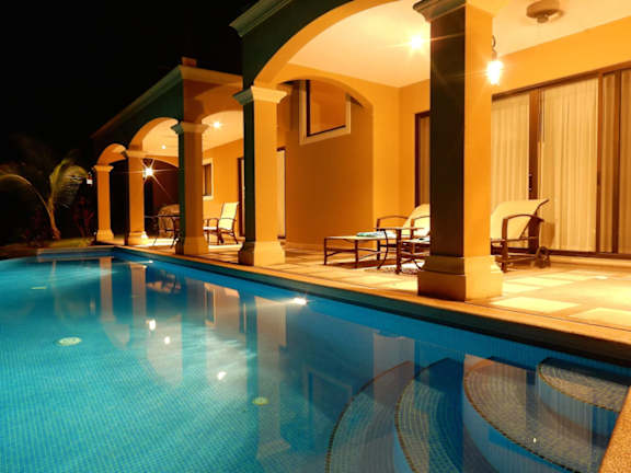 A pool in a house with lights on.