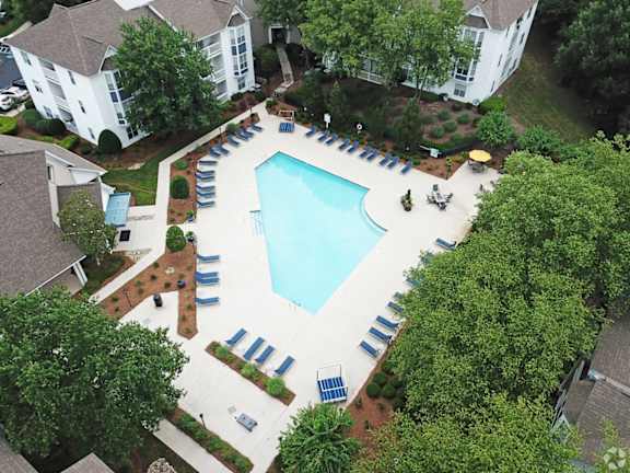 An aerial view of a pool surrounded by trees and chairs.
