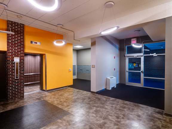 A hallway with a yellow door and a white trash can at Edmands House, Framingham, 01701