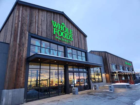 The Whole Foods Market storefront is made of wood and has a glass entrance.
