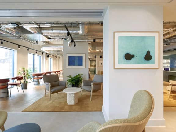 a lobby with chairs and tables and a painting on the wall