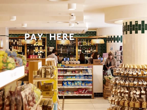 a supermarket with people in it and a pay here sign