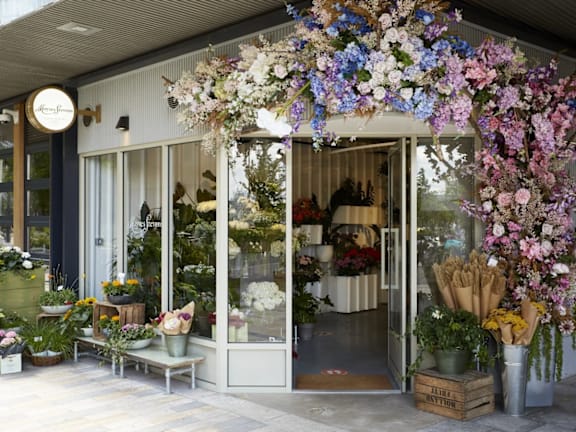 the front of a flower shop with a canopy of flowers