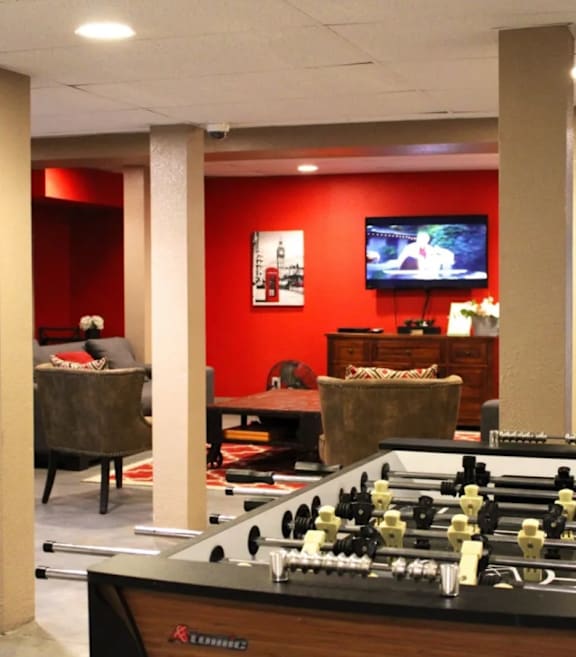 A foosball table is in the middle of a room with a couch and a television.
