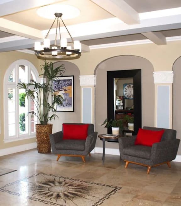 A leasing office room with a grey sofa and a red pillow.