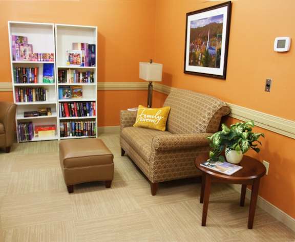 A living room with a couch, chair, ottoman, and bookshelves.