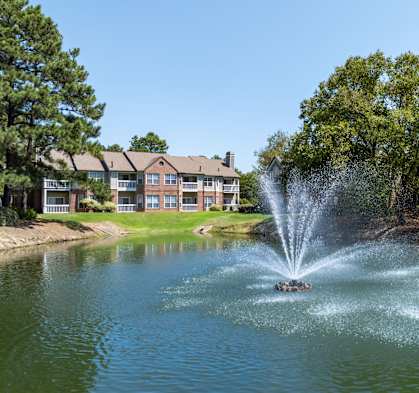 a fountain in the middle of a lake with an apartment building in the background at The Grove Germantown Apartments, Tennessee, 38138