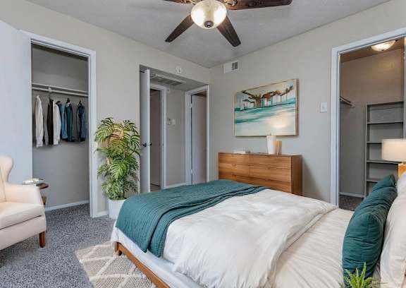 A bedroom with a bed, chair, and a painting on the wall.