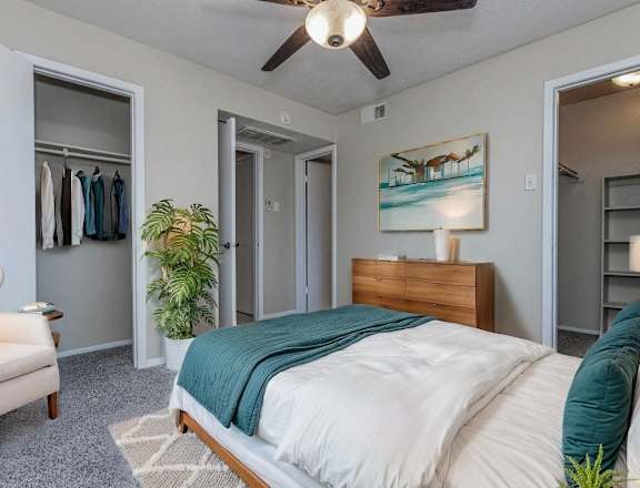 A bedroom with a bed, chair, and a painting on the wall.