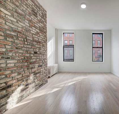 A room with a brick wall and wooden flooring.