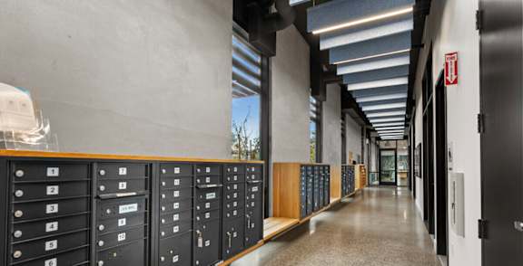 A long hallway with black lockers on the side and doors on the right.