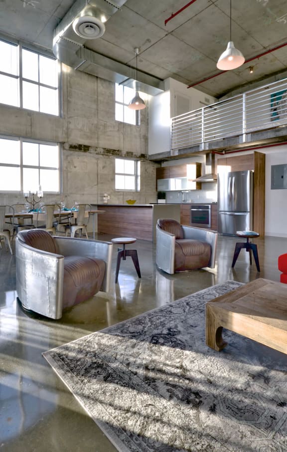 a large living room with leather chairs and a kitchen in a loft