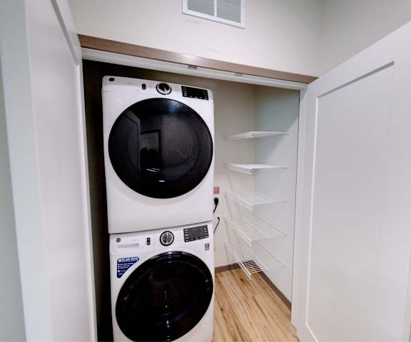 The laundry room with shelves, a washer, and a dryer at Van Buren East Apartment Homes. 
