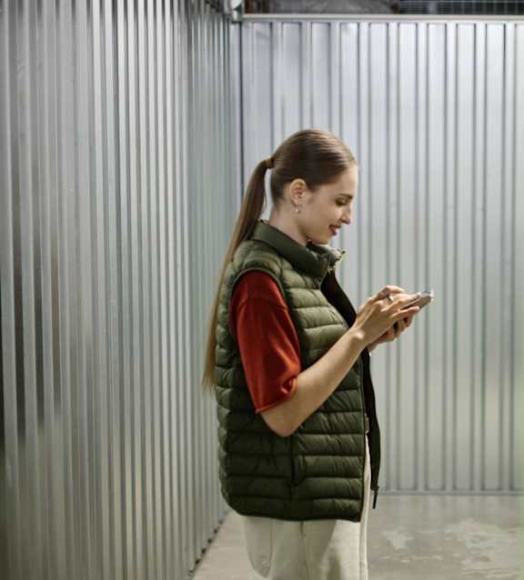 A person in a striped shirt and green vest is using a tablet.