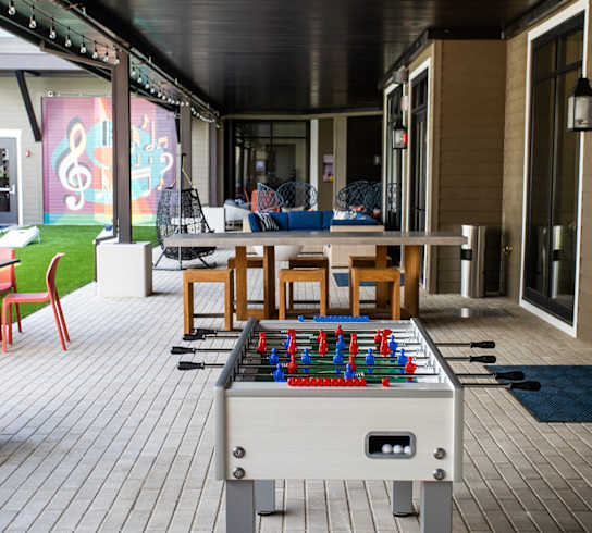a foosball table in an outdoor patio area with chairs and tables at Lyric at Norton Commons Apartments, Prospect, Kentucky