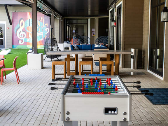 a foosball table in an outdoor patio area with chairs and tables at Lyric at Norton Commons Apartments, Prospect, Kentucky
