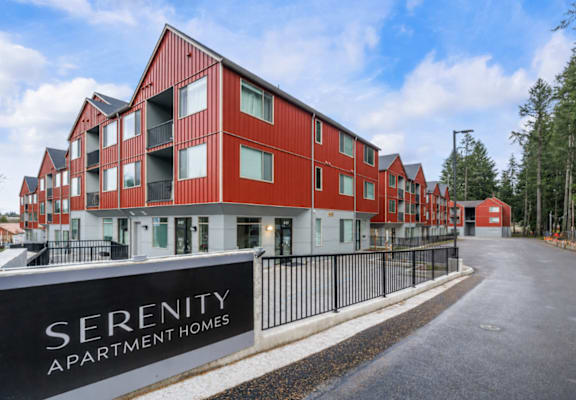 Apartment complex named Serenity with red buildings and black fencing.