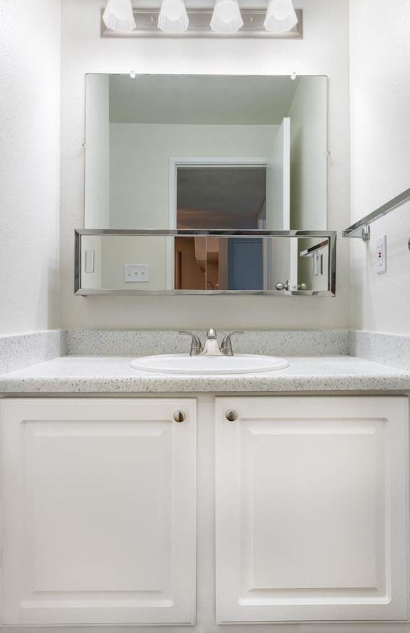 a bathroom with white cabinets and a sink and a mirror