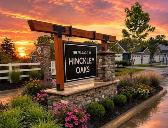 A sign that says "The Village at Hinckley Oaks" is in front of a house.
