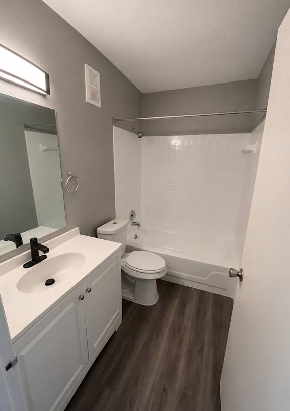 A white toilet sits in a bathroom next to a sink and mirror.