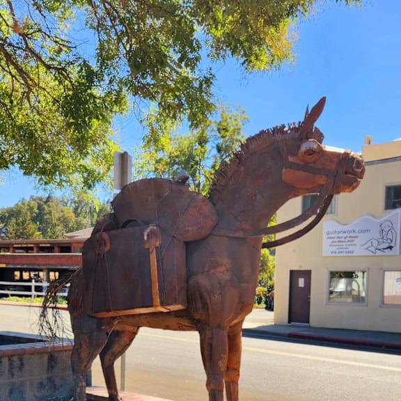 A bronze statue of a horse is in the foreground of the image.