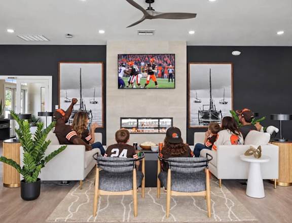 A family is watching a football game on a large TV in a modern living room.