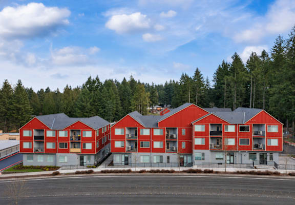 A row of red apartment buildings with trees in the background.