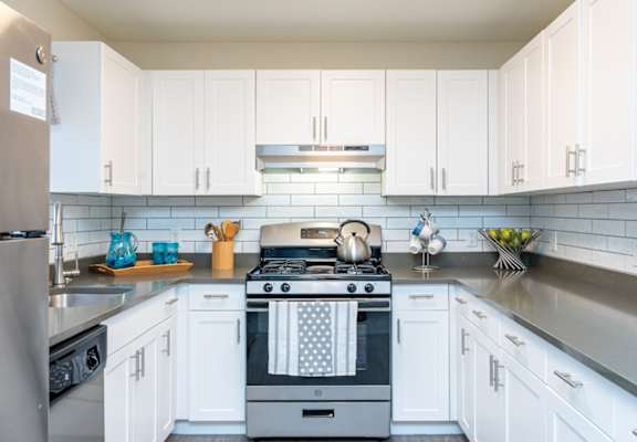 A modern kitchen with white cabinets and a stove top oven.