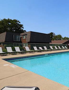 A large swimming pool with a metal ladder and white lounge chairs.