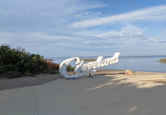 A large sign that says "Cleveland" is in front of a body of water.