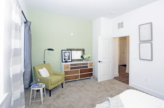 Model bedroom unit with carpeted floors and seating area