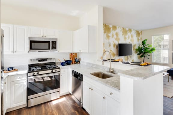 A modern kitchen with a refrigerator, sink, and microwave at The Residences at Stevens Pond