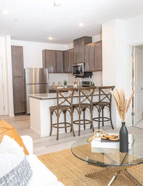a living room with a kitchen with a bar and a tv
