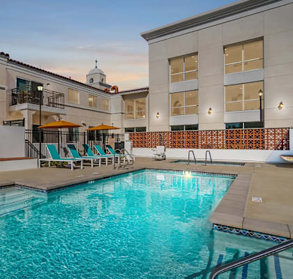 A large indoor swimming pool with a hot tub and lounge chairs.