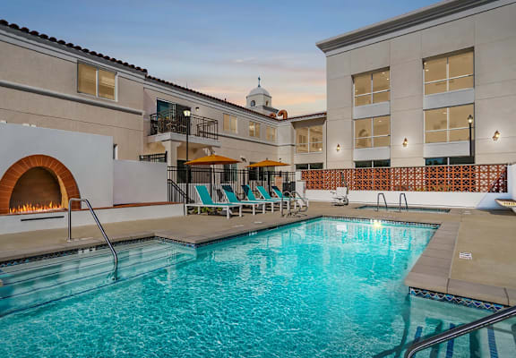 A large indoor swimming pool with a hot tub and lounge chairs.