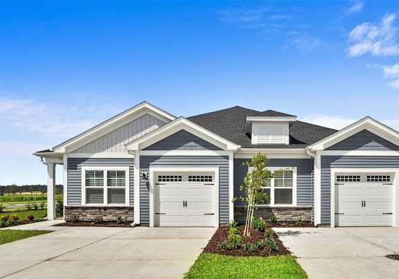 A two-story house with a grey roof and white garage doors. at Stepping Stone at Bridgewater Apartments, Little River