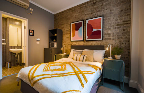 a bedroom with a bed in front of a brick wall