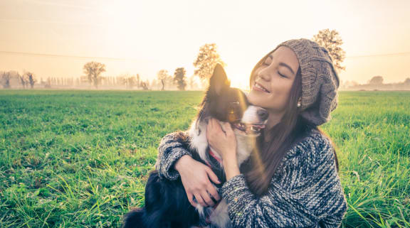 a woman sitting on the grass with her dog