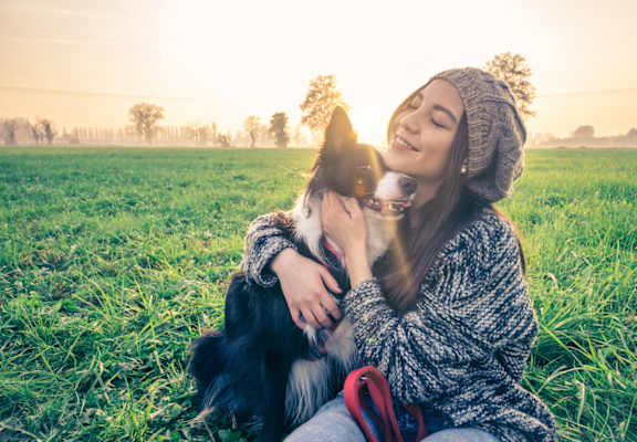 a woman sitting on the grass with her dog