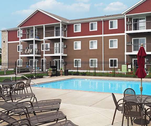 an outdoor pool area with tables and chairs near an apartment building