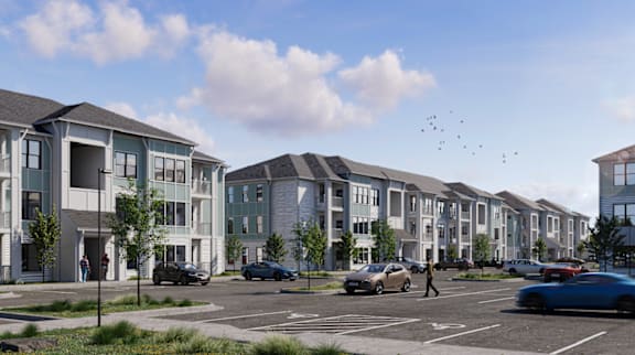 A row of modern townhouses with cars parked in front.