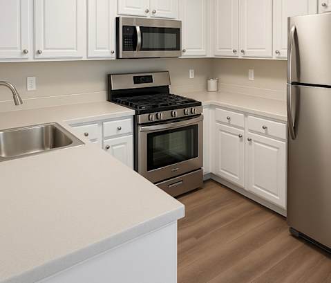A kitchen with white cabinets and a stainless steel refrigerator.