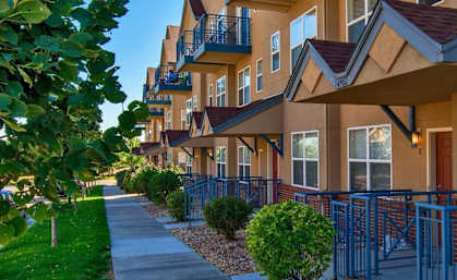 A row of houses with a sidewalk in front.