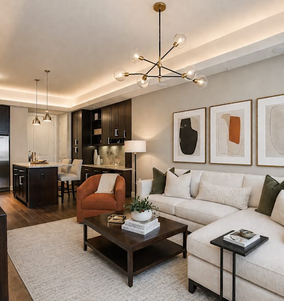 A modern living room with a white couch, a coffee table, and a chandelier. at Uptown by Onni Apartments, Apartments, Dallas, TX