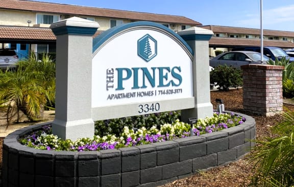 an flag flies above the pines apartments sign in front of a building
