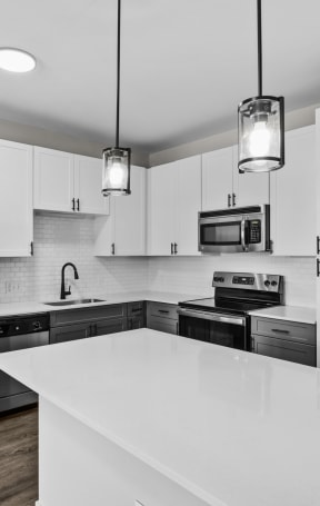 a black and white photo of a kitchen with white countertops and black appliances