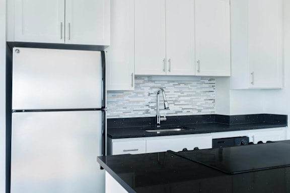 A modern kitchen with a black countertop and white cabinets at Skye at Belltown Apartments, 98121
