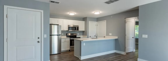 an empty kitchen with an island and a stainless steel refrigerator