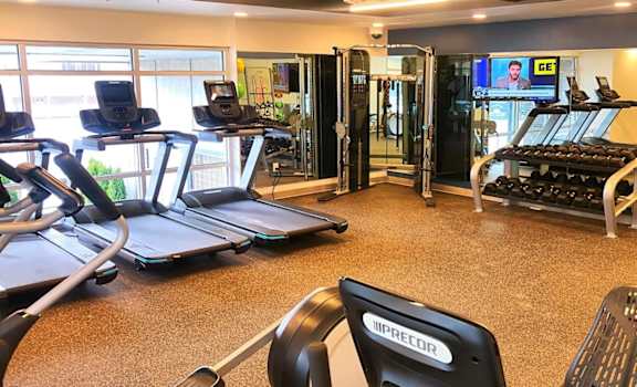 a gym with cardio equipment and a tv